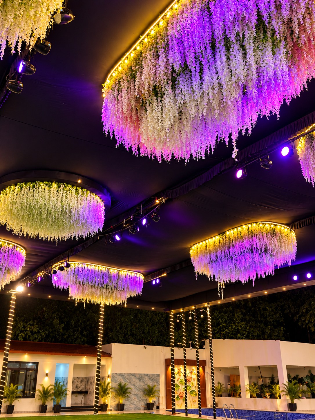 Illuminated hanging floral installations above the celebration lawn